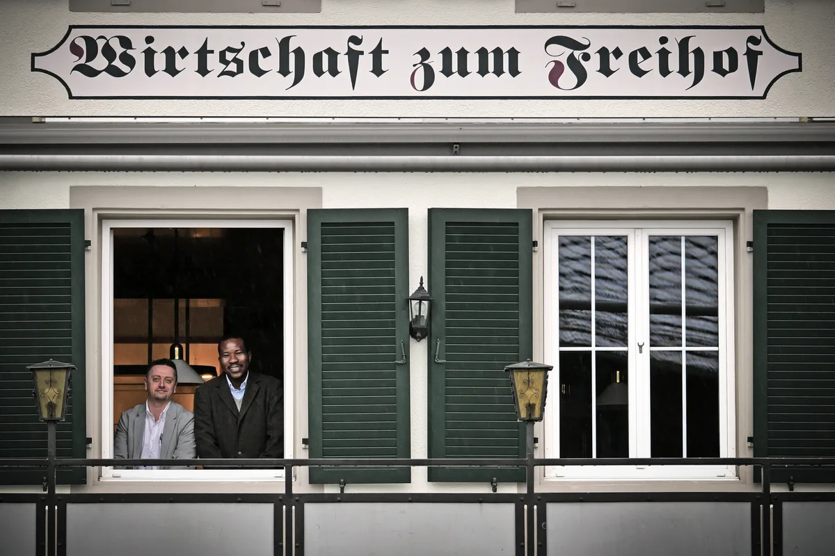 Zwei Männer blicken aus dem Fenster eines Restaurants.